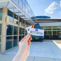 Hand holding community center pass and library card with the Worthington Community Center exterior in the background