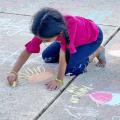 Child drawing with chalk outdoors