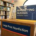 Signs that say: Magnifying glasses available here; and Large Print Nonfiction