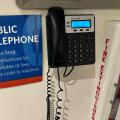 Telephone on wall next to a sign with details about use of public telephone