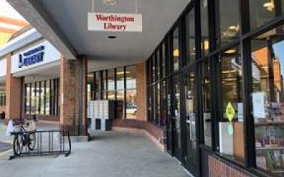 Sidewalk under awning outside Worthington Park Library with bike rack and pick-up lockers