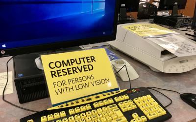 Computer with sign that reads 'Computer Reserved for persons with low vision"