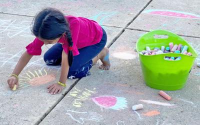 Child drawing with chalk outdoors