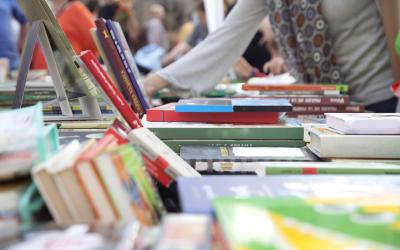 People looking at books stacked on tables