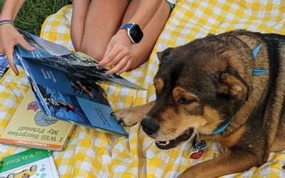 Child reading to a dog outdoors